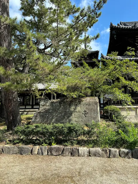 古い寺院の境内の景観、背後に木々と古い建物が見える
