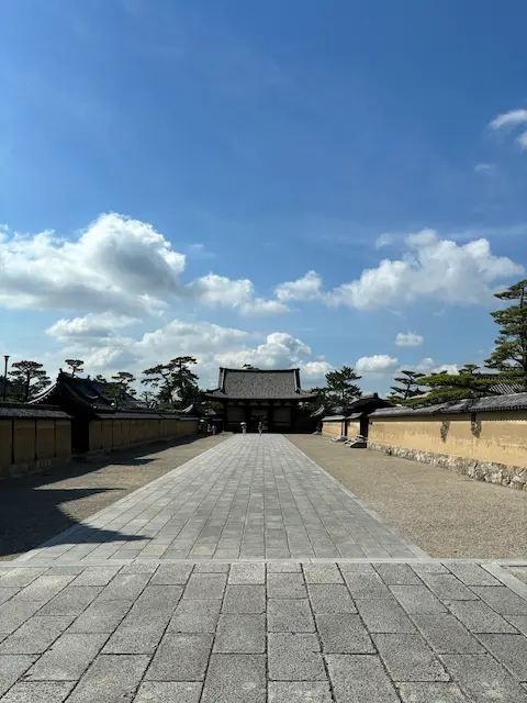 庭園に続く石畳の道と空に浮かぶ雲を背景にした伝統的な日本の建物