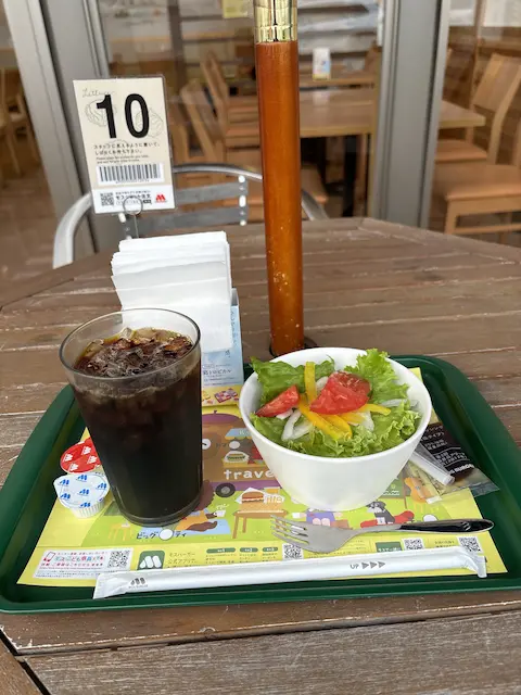 テーブルの上に置かれたアイスコーヒーとサラダが載ったプレート。背景にはスタンドの番号10と椅子が見える。