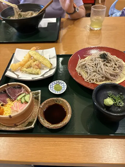 そば、天ぷら、刺身の盛り合わせがある日本食の定食プレート