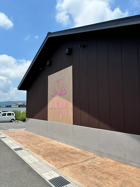 黒い外壁の建物に、ピンクのロゴが掲げられている様子